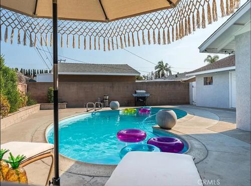 a swimming pool in a backyard with an umbrella at Stunning Oasis with Pool by Disneyland and Knotts in Buena Park