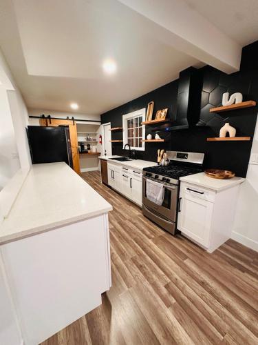 a kitchen with black and white appliances and wooden floors at Stunning Oasis with Pool by Disneyland and Knotts in Buena Park