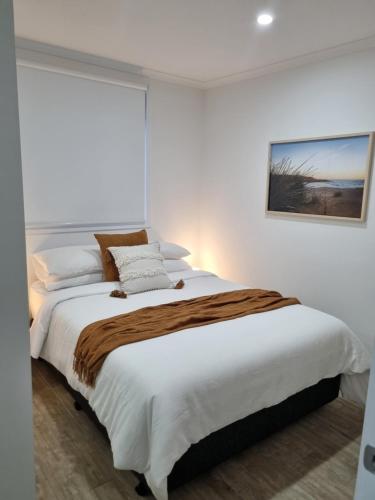 a bedroom with a large bed with white sheets at 3rd On Troon in Normanville