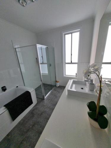 a white bathroom with a tub and a sink at 3rd On Troon in Normanville