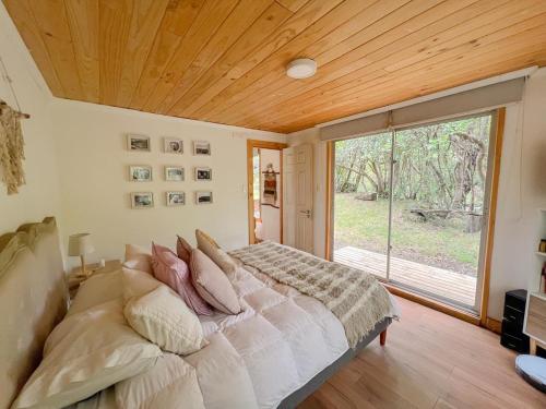 a bedroom with a large bed and a large window at Cabaña de Montaña con Río in Puhala