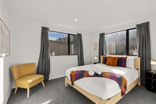 a bedroom with a bed and a chair at Shotover View - Family friendly close to Coronet Peak in Frankton Wharf