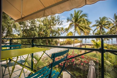 a balcony with chairs and a table and palm trees at Appartement Le Galawa avec les pieds dans l'eau à Saline-les-Bains pour 5 personnes in La Saline les Bains