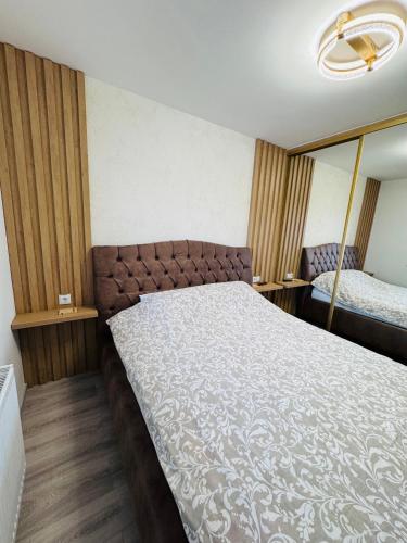 a bedroom with a large bed and a mirror at Apartman Jaćimović in Doboj