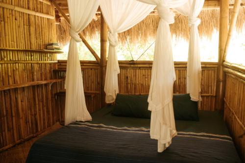 a bed in a room with a mosquito net at Betelnut Eco-Lodge Sumba in Lambatama