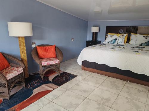 a bedroom with a large bed and two chairs at Casa Hortensia in Nicoya