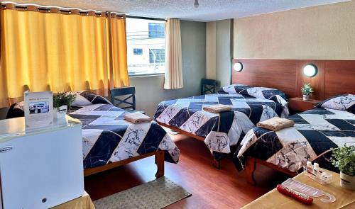 a hotel room with two beds and a window at Hostal La Estación Quito in Quito