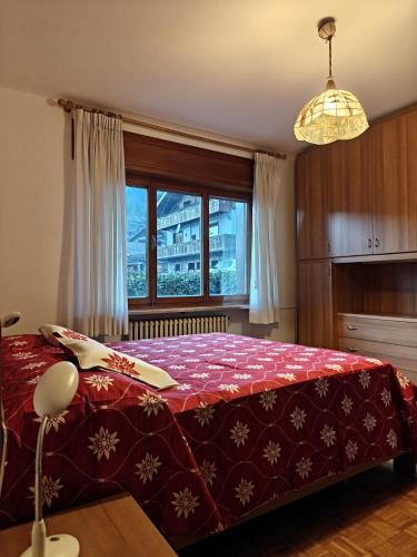 a bedroom with a large red bed with a window at Casa Lassù in Pieve di Cadore