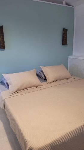 two beds in a bedroom with a blue wall at Suíte Cambucá in Praia do Bananal