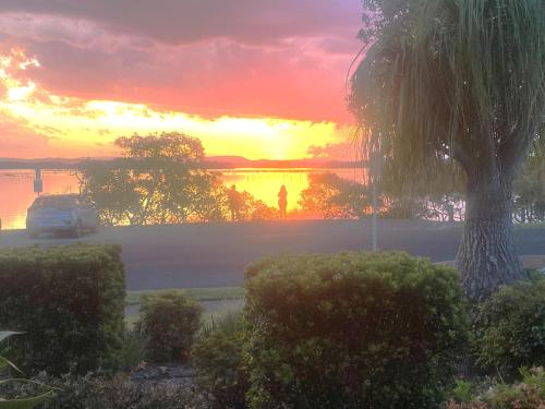 a car parked in front of a lake at sunset at The Lakeside Garden in Forster
