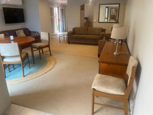 a living room with a table and chairs and a couch at The Lakeside Garden in Forster