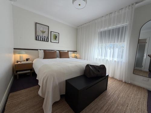 a white bedroom with a large bed and a desk at Villa Croissant 2br located within Cypress Lakes Resort in Pokolbin