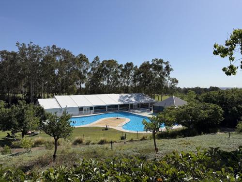a large building with a swimming pool in a field at Villa Croissant 2br located within Cypress Lakes Resort in Pokolbin