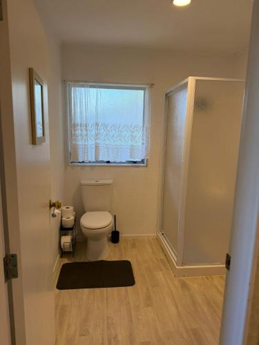 a bathroom with a toilet and a window and a shower at Villa in Bellevue in Tauranga