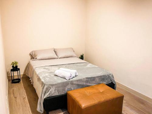 a small bedroom with a bed and a stool at Vive Medellin apartamento in Envigado