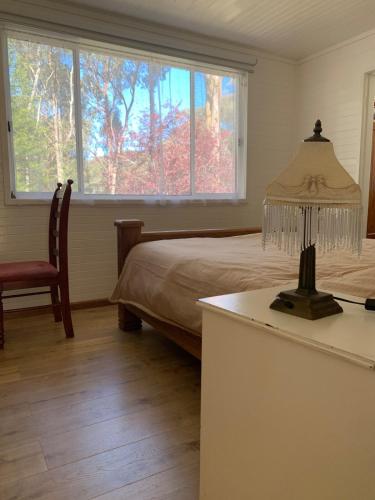 a bedroom with a bed and a table with a lamp at Retreat in a beautiful forest! in McMahons Creek