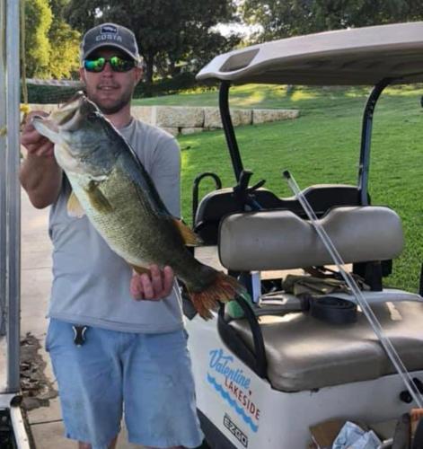 a man holding a fish in front of a golf cart at Valentine Lakeside in Kingsland