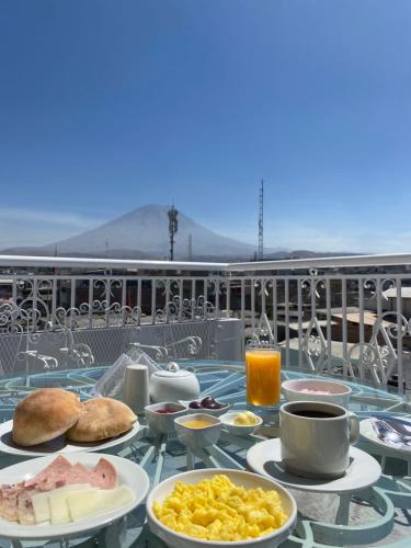 a glass table with breakfast food on a balcony at Hotel San Francisco INN in Arequipa
