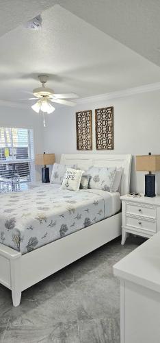 a white bedroom with a large bed and a table at Beach Condo in Clearwater Beach