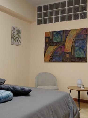 a bedroom with a bed and a chair and a painting at La Terrazza Apartment in Cosenza