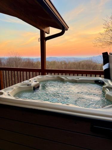 a jacuzzi tub with a sunset in the background at Paws at the Peak in Beech Mountain