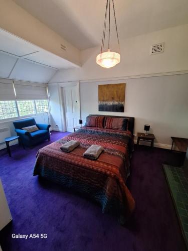 a bedroom with a large bed and a blue couch at The Gables - Circa 1880 - Classic Bowral Property in Bowral