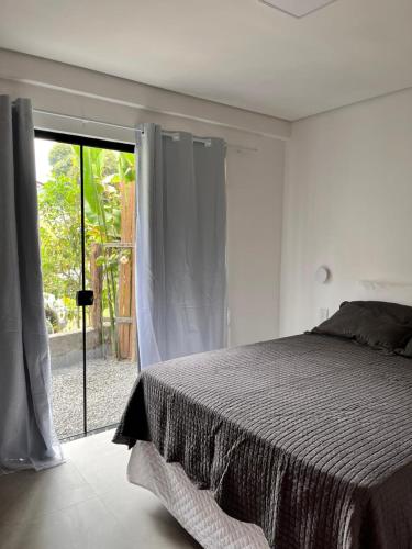 a bedroom with a bed and a large window at Casa Liz in Itacaré