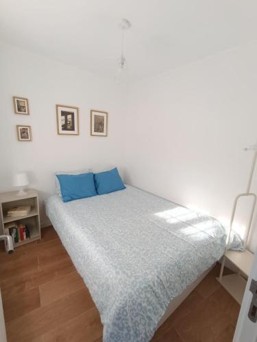 a bed with blue pillows in a white room at Casa do Ferro de Engomar in Samouco