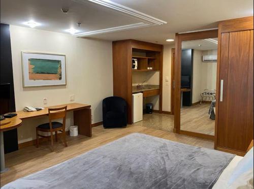 a room with a bed and a desk and a table at Lindo flat Grand Mercoure triplo in Brasília