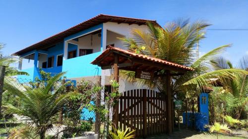 a blue and white house with a gate and palm trees at Recanto Ebenézer in Taipu