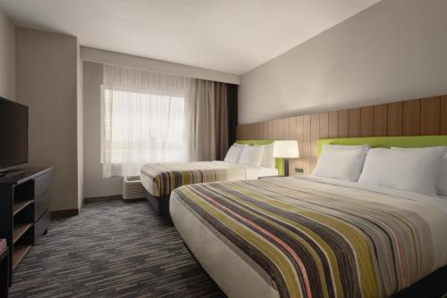 een hotelkamer met twee bedden en een televisie bij Country Inn & Suites by Radisson, Champaign North, IL in Champaign