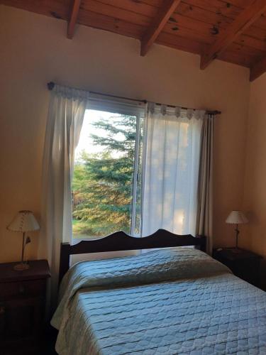 a bedroom with a bed and a large window at Balcón del Cerro Cabañas in La Falda