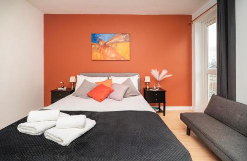 a bedroom with a bed with orange walls and a couch at 5 of 5 Room Cozy, spacious and modern in Camden Town in London
