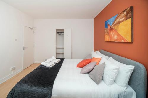 a bedroom with a bed with pillows and a painting on the wall at 5 of 5 Room Cozy, spacious and modern in Camden Town in London