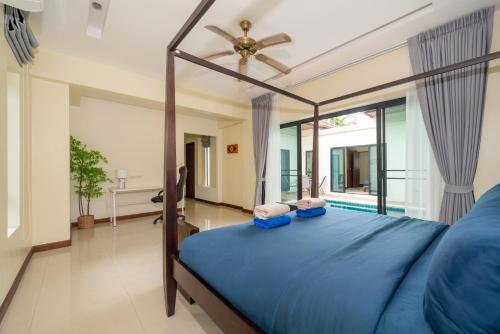 a bedroom with a blue bed and a large window at Rawai - 3 BR Private Pool Villa - Phoomjai Villa in Rawai Beach