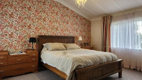 a bedroom with a bed and a wall with floral wallpaper at La Casa in Napier