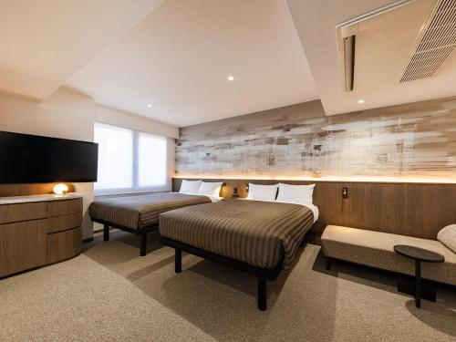 a hotel room with two beds and a flat screen tv at The OneFive Tokyo Kameido in Tokyo