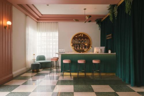 a bar in a room with green curtains and stools at Le Particulier Miami in Miami Beach