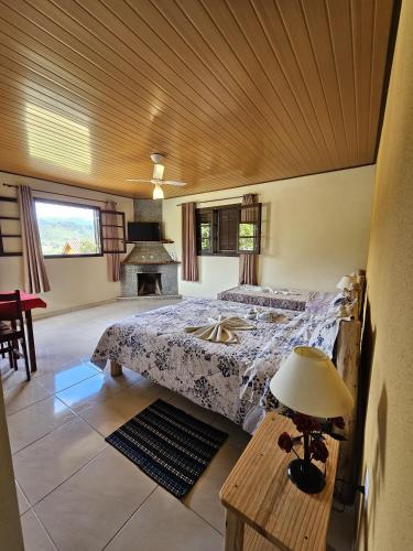 a bedroom with a bed and a table with a lamp at Chalé Canário da Terra 2 in Visconde De Maua