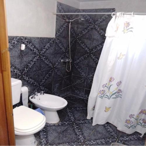 a bathroom with a toilet and a shower curtain at Claro de Luna in Los Reartes