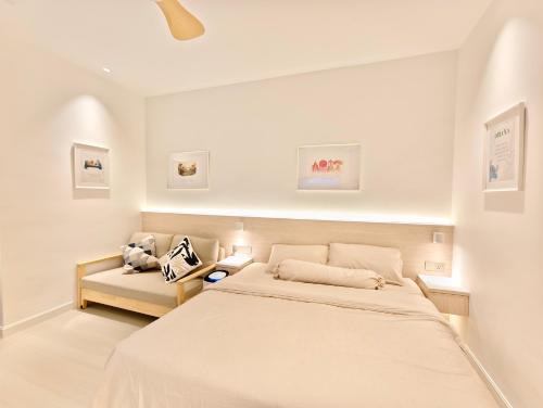 a white bedroom with a bed and a chair at 22 Macalisterz - King Suite - 65"QLED TV - Disney - Pop Corn - Sky Pool in George Town