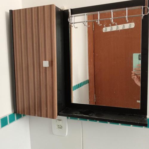 a bathroom mirror with a wooden door in a bathroom at Enseada Perto da praia Guarujá com vaga de garagem in Guarujá