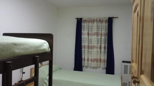 a bedroom with a bed and a window with curtains at Flores y limones in Villa Gesell