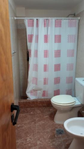 a bathroom with a toilet and a shower curtain at Flores y limones in Villa Gesell