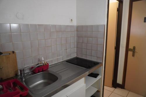 a kitchen with a sink and a tiled wall at Camellia 2 Duplex in Sainte-Anne