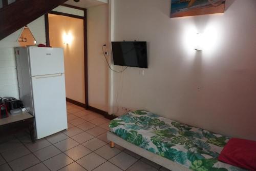 a room with a refrigerator and a tv on the wall at Camellia 2 Duplex in Sainte-Anne