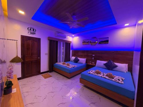 a room with two beds and a ceiling with purple lights at Mina Grande Beach Cottages in El Nido