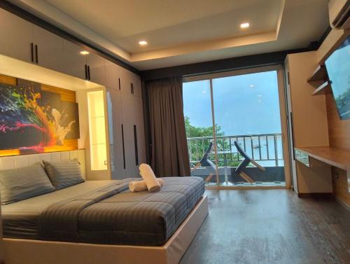 a bedroom with a large bed and a large window at โรงแรม ชาโตว์วิสต้า in Chon Buri