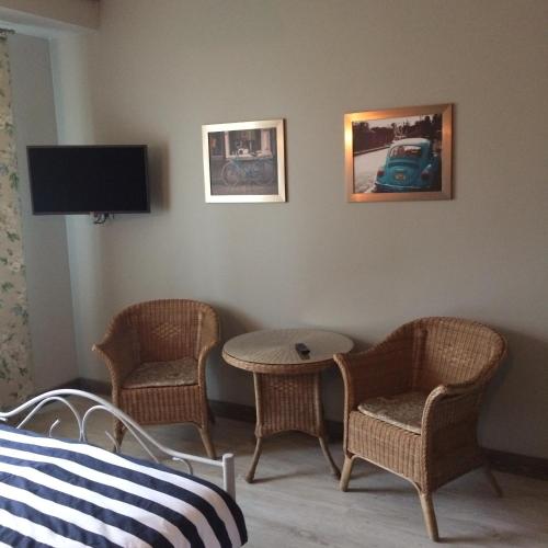 a room with two chairs and a table and a tv at Dzirnaviņas in Biksti