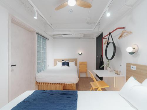 a bedroom with two beds and a table and a desk at The Road Mini Hotel in Seoul
